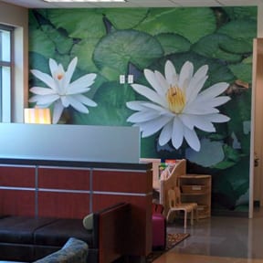 A room with a large wall mural of water lilies.