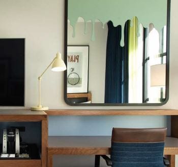 A mirror sitting on top of a wooden desk.