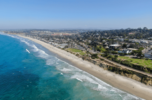 Aerial view of a coastal city with a beach and ocean waves.